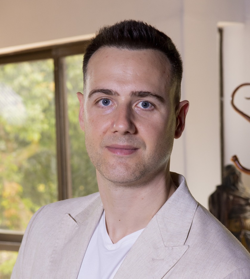Blake Miner in a light blazer, photographed by a window